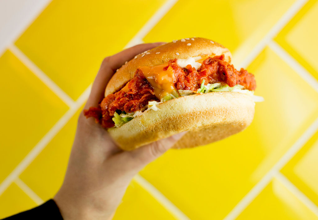 Hand holding burger on a yellow tiled background Liverpool food photographer