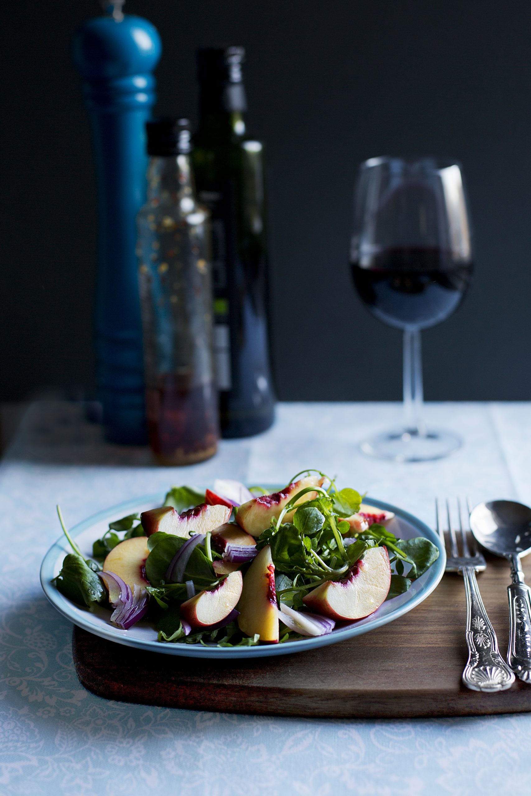 Peach and watercress salad with a Peppermill, bottles and wine in the background food photographer Liverpool Manchester Patricia Niland